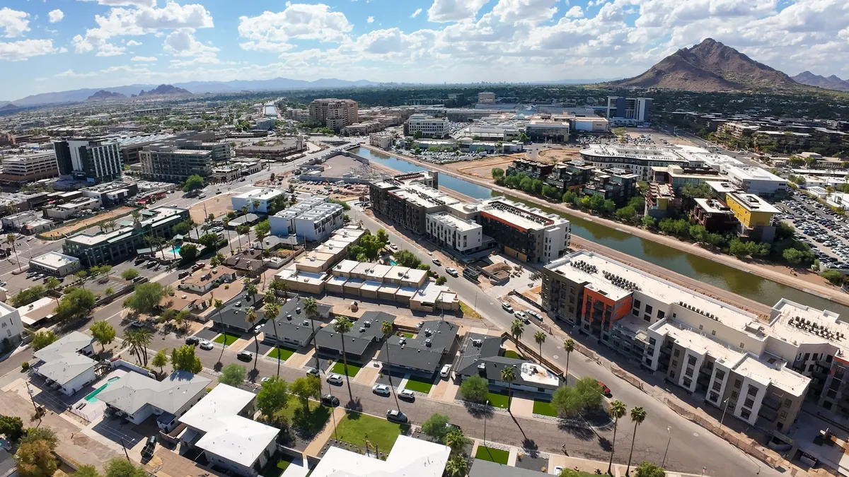A dynamic exterior scene with a mountain background, a river, modern residential buildings, commercial structures, and palm trees. The area feels fresh and full of social opportunities, ideal for groups looking to experience both relaxation and Scottsdale’s buzzing nightlife.