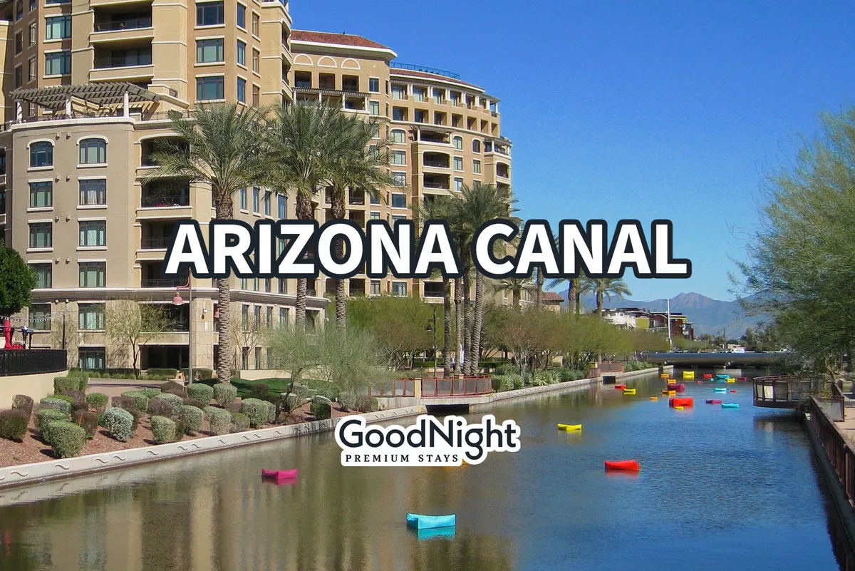 The Arizona Canal is flanked by colorful boats, tall palm trees, and contemporary residential buildings. The area is lively and bright, ideal for walking, boating, and enjoying waterfront activities under the Arizona sun.