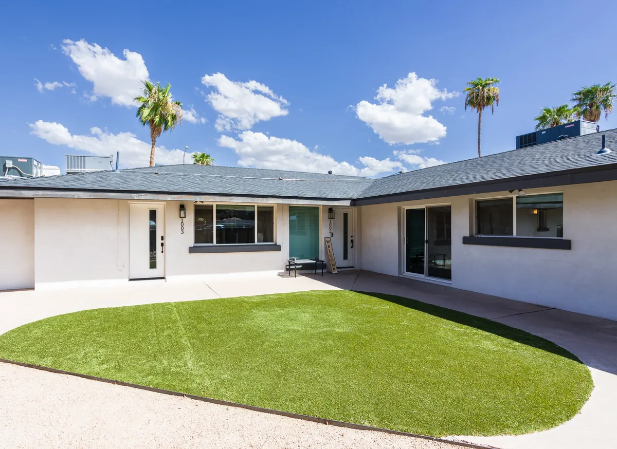 This image features a green lawn bordered by palm trees and shows a clear entrance door, conveying a sense of privacy and security. The bright, sunlit yard suggests a welcoming and cheerful space ideal for outdoor activities.